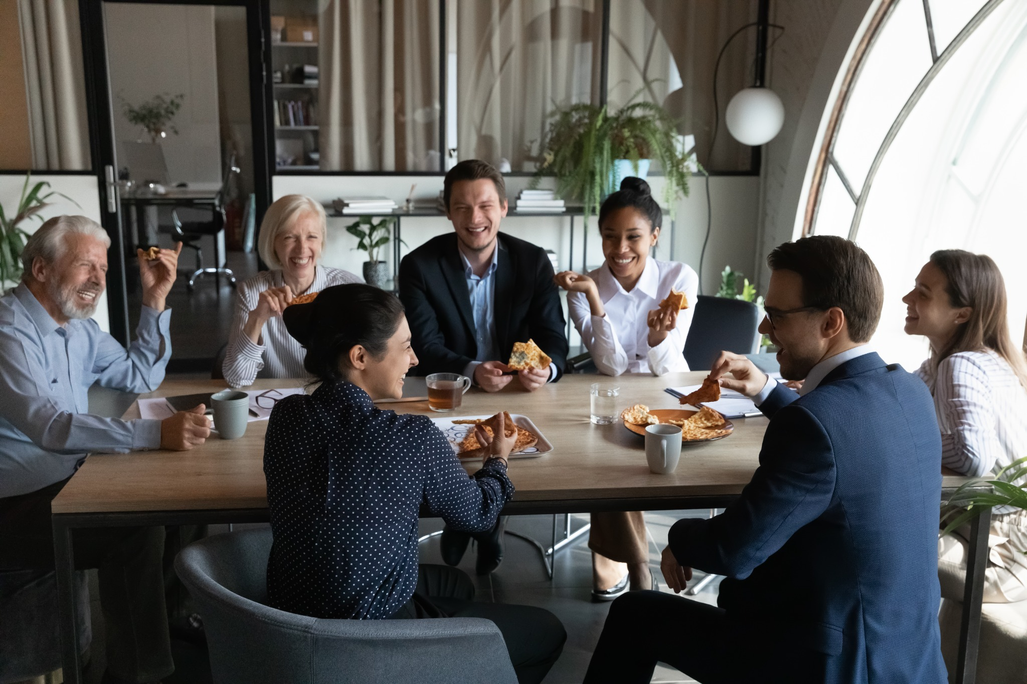 Office team enjoying catered lunch during a corporate meeting, representing the convenience and comfort of hosting workplace events