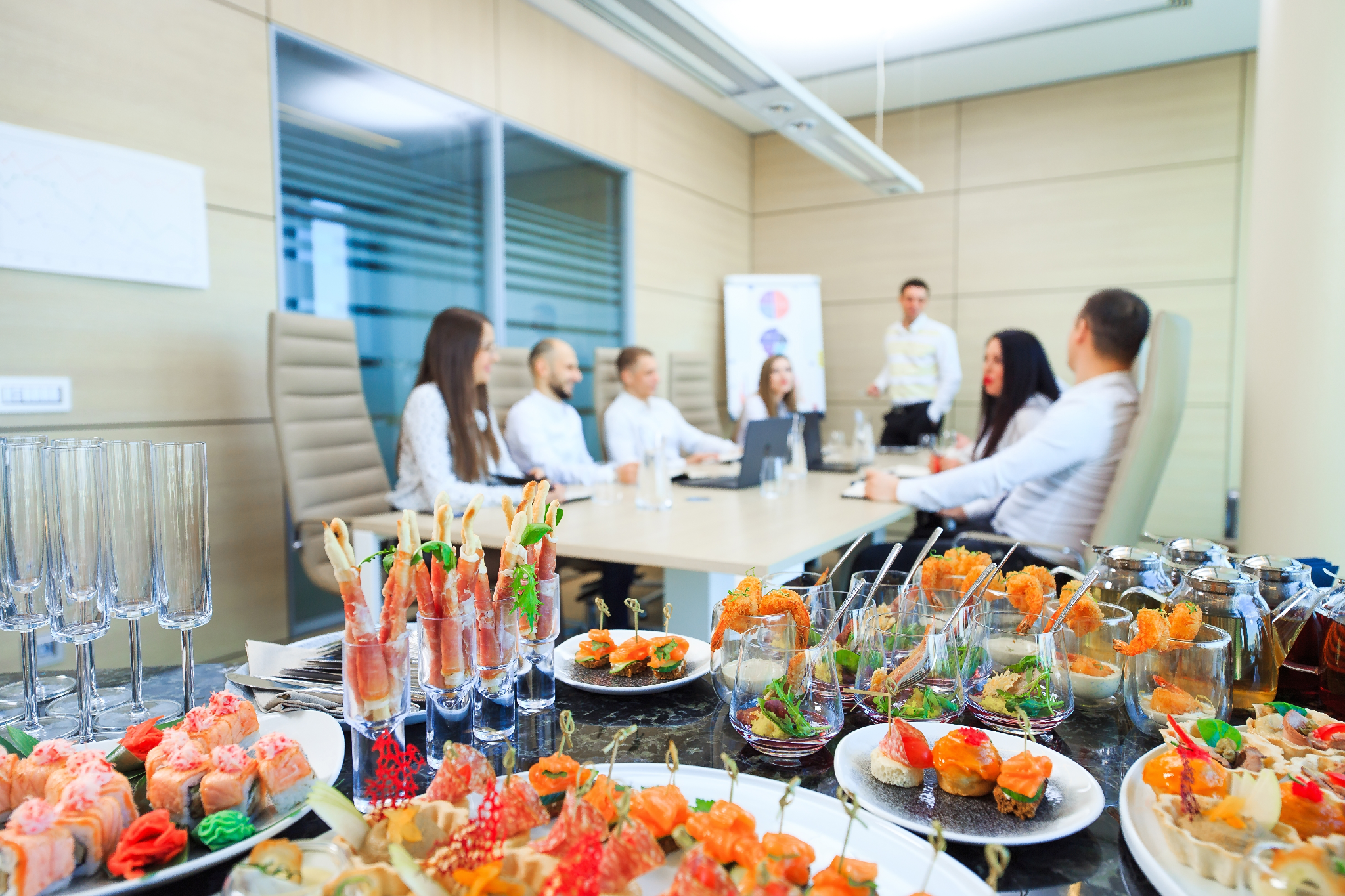 Corporate catering setup with appetizers and a business meeting in progress, representing transparent catering services without hidden fees